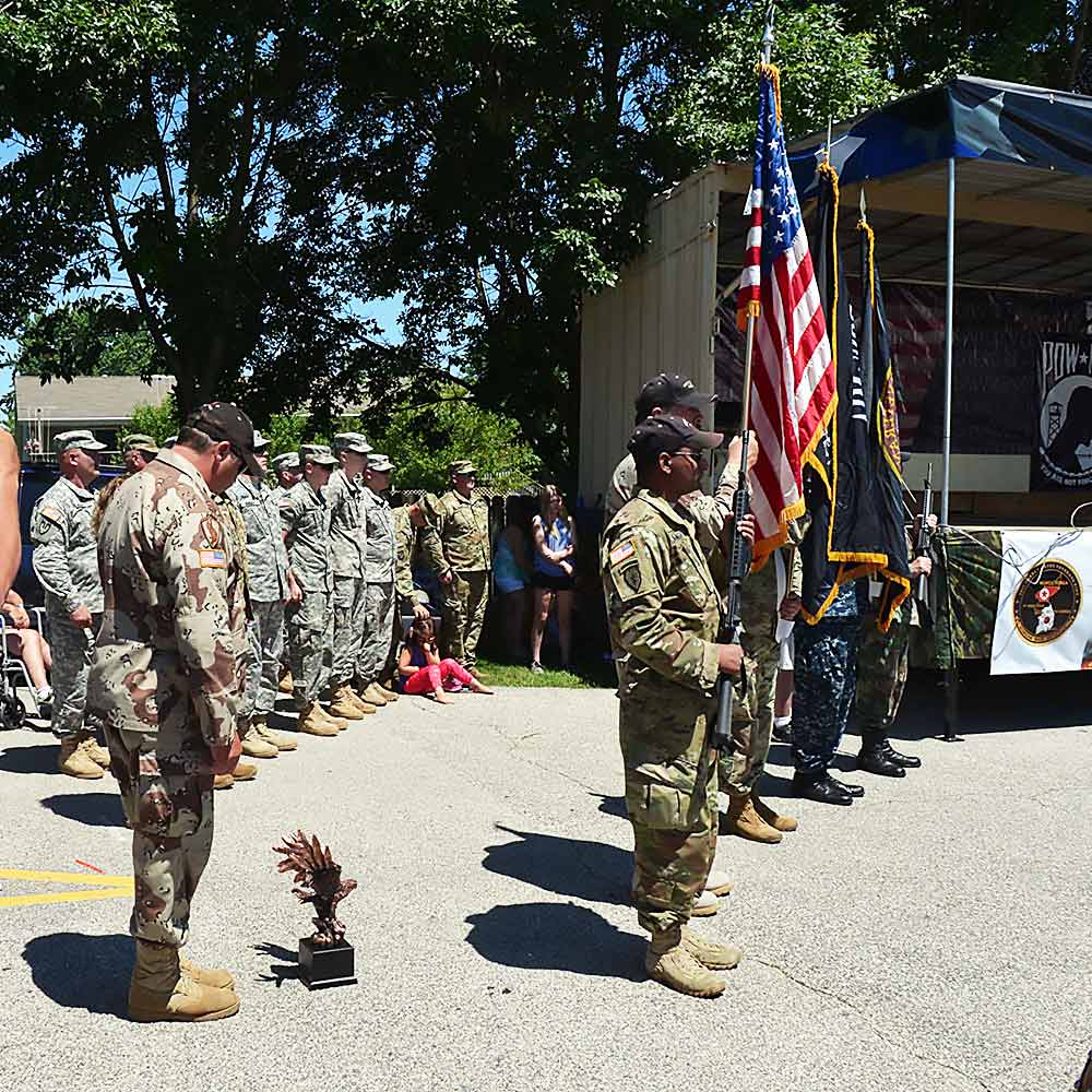 Servicemen gathered around the US flag.